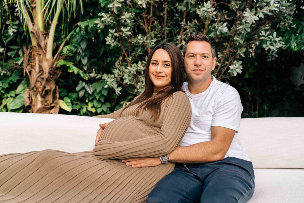 pregnant mom and dad sitting on a lounge chair outside